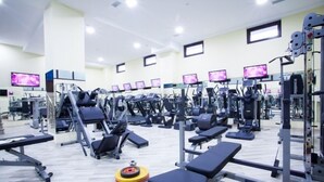 Et fitnesscenter med forskellig træningsudstyr, styrkeløftstationer og løbebånd.