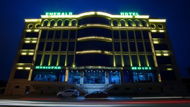 Et hotel med et tydeligt skilt, der viser "Emerald Hotel", en restaurant og en indgang med trappe.
