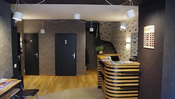 Un área de recepción con un mostrador de madera, una puerta negra y una escalera con papel tapiz estampado.