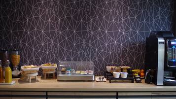 A breakfast buffet setup with various food items and a coffee machine.