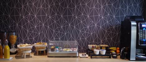 A breakfast buffet setup with various food items and a coffee machine.