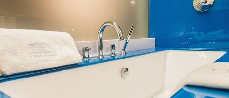 A modern bathroom with a white sink, chrome faucet, and a blue accent wall.