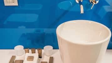 Un bagno con un lavandino bianco di grandi dimensioni, una parete blu e articoli da toilette disposti sul mobile.