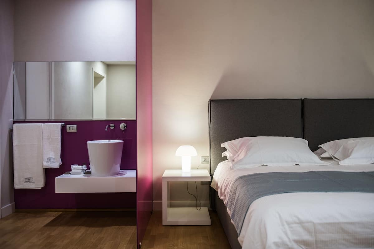 Ein Schlafzimmer mit Bett, Nachttisch, Lampe und Spiegel.