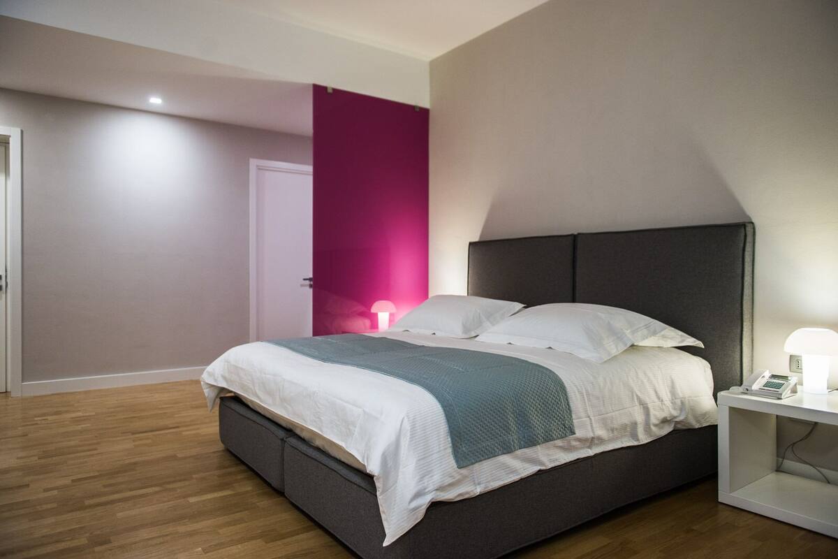 Ein modernes Schlafzimmer mit einem Bett, einem Nachttisch und einem Beistelltisch mit einer Lampe.