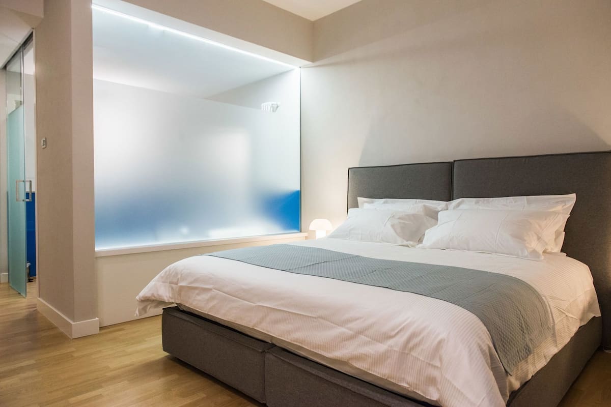 Ein modernes Schlafzimmer mit einem großen Bett, einem Nachttisch und einer Wandleuchte.