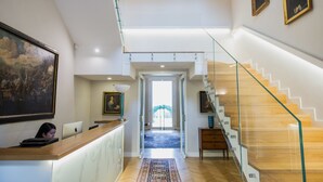 A modern interior with a reception desk, a staircase, and artwork on the walls. - Villa Pulejo (Messina)