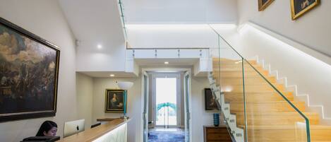 Un interior moderno con una recepción, una escalera y obras de arte en las paredes.