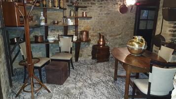 A rustic room with exposed brick walls, wooden furniture, and shelves filled with bottles and copper pots.