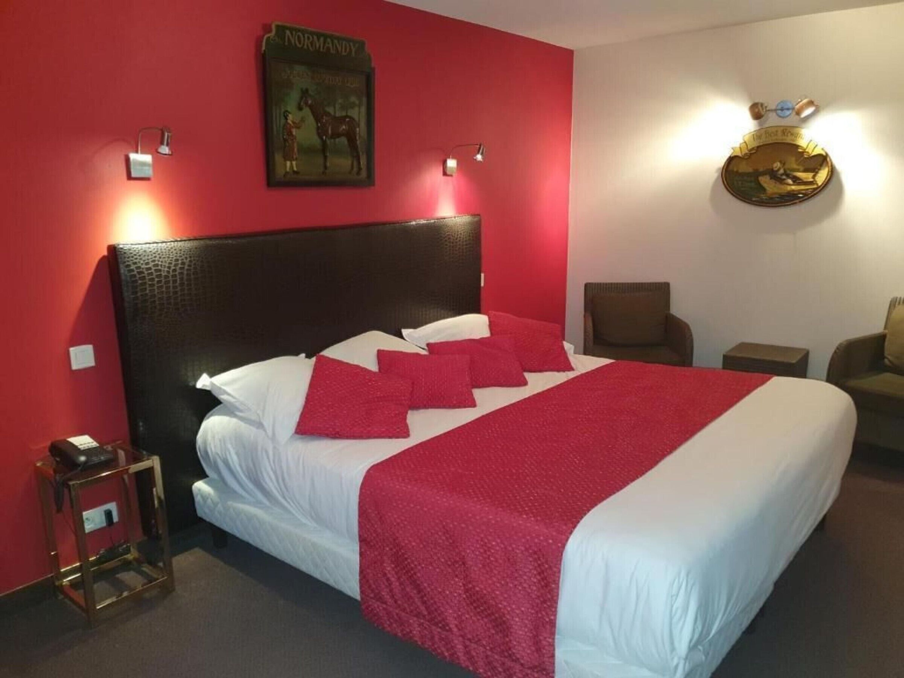 Una habitación de hotel con una cama grande, paredes rojas y un cuadro enmarcado en la pared.