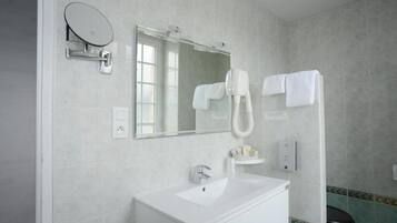 Un baño con lavamanos blanco, un espejo, cabezal de ducha de mano y un inodoro.