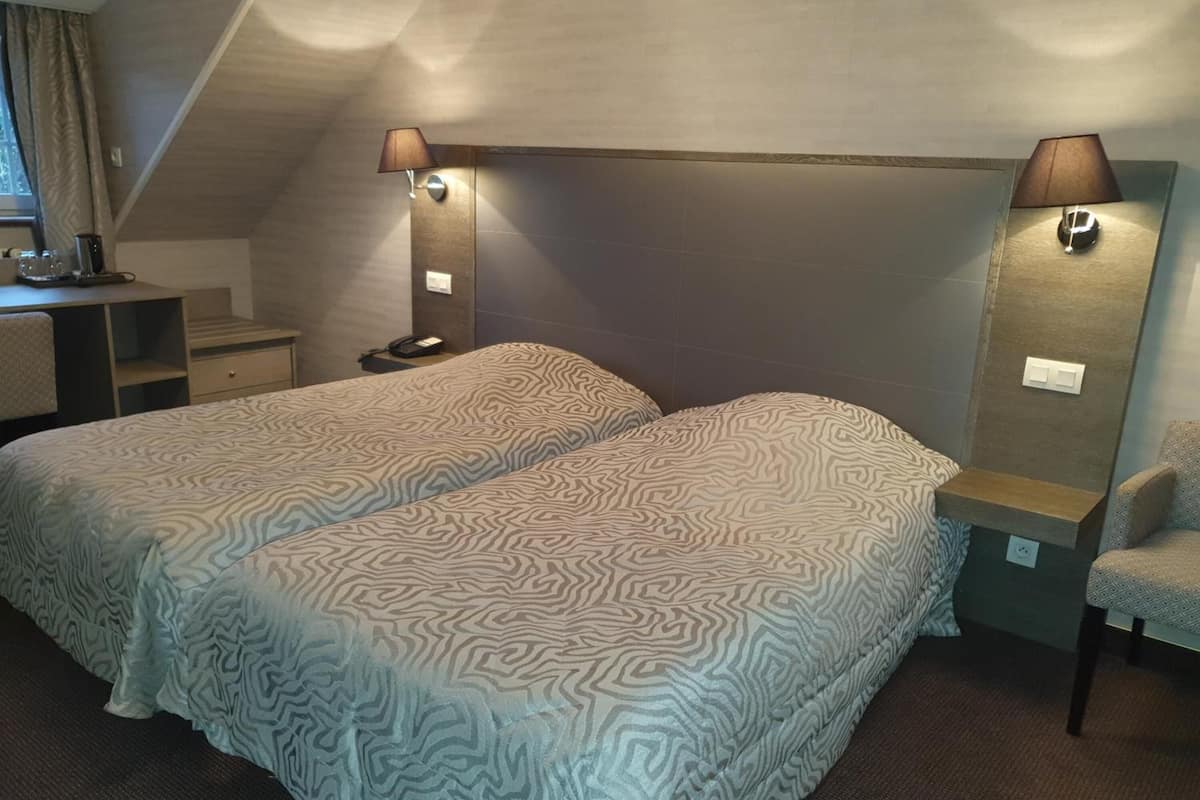 Habitación de hotel con dos camas, un escritorio, una silla y un espejo.