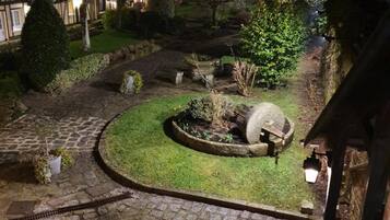 Un patio de piedra con un jardín circular, una gran fuente de agua y un sendero de piedra.
