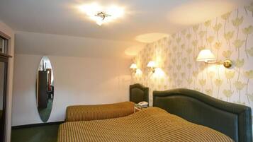 Habitación de hotel con dos camas, un espejo y lámparas fijadas a la pared.