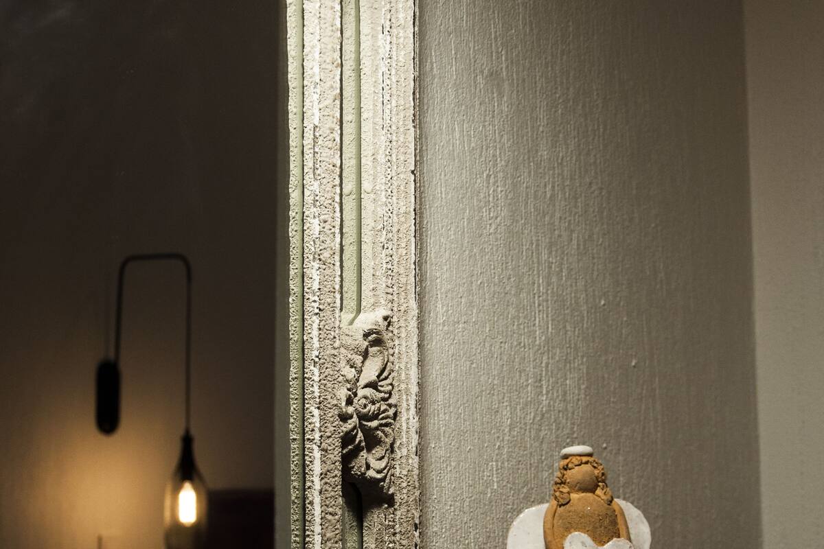 A mirror with ornate detailing and a small angel figurine on a black table beside it.