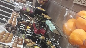 Un buffet proposant une variété de plats et de boissons, notamment des fruits, des pâtisseries et des boissons servies dans des verres.