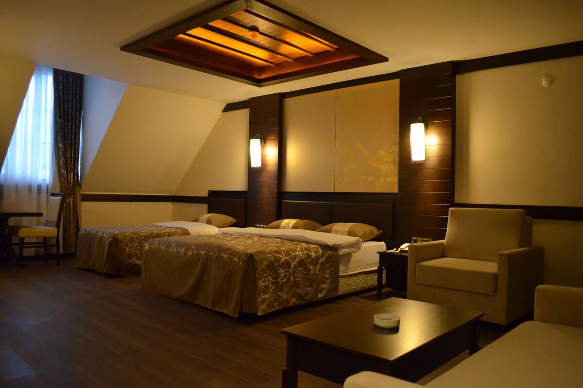 Habitación de hotel con dos camas, un sofá, una mesa de centro y un escritorio.