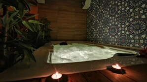 Un espace de détente avec un jacuzzi, deux bougies et un mur décoré de motifs.
