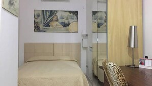 Hotellihuone, jossa on sänky, seinällä taulu, peili, leopardikuviollinen tuoli ja työpöytä, jossa on lamppu.