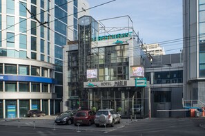 A modern building with a glass facade, a sign for 'Marlin Hotel', and several parked cars in front. - Marlin Hotel (Odesa)