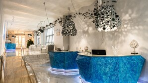 A modern hotel lobby with marble flooring, two blue marble reception desks, and unique ceiling art. - Marlin Hotel (Odesa)
