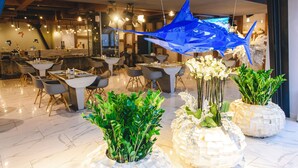 A modern dining area with marble flooring, contemporary furniture, and decorative plants. - Marlin Hotel (Odesa)