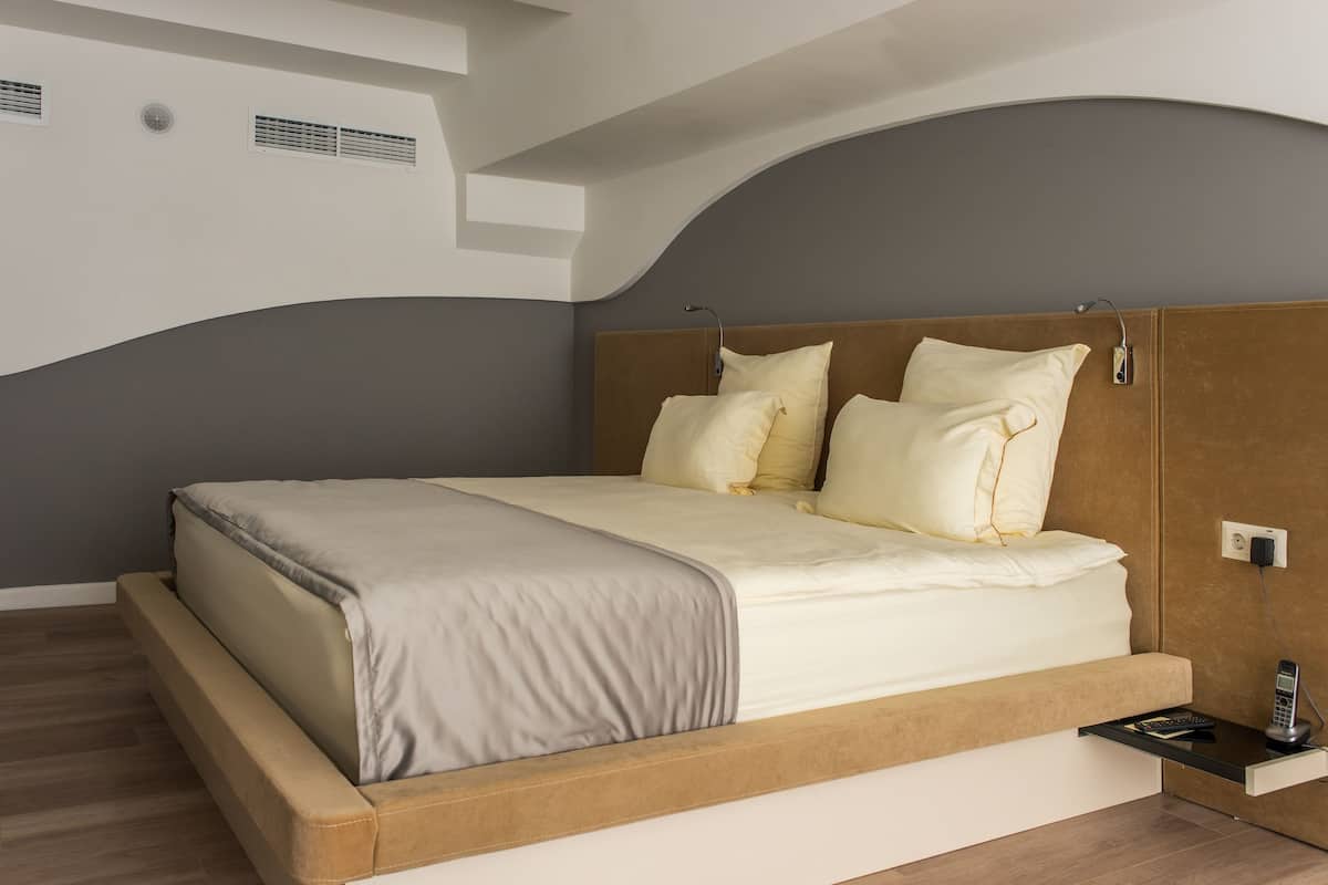 A modern bedroom with a bed, bedside table, and a built-in shelf.