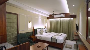A hotel room with a bed, a desk, a chair, a TV, and a ceiling fan.