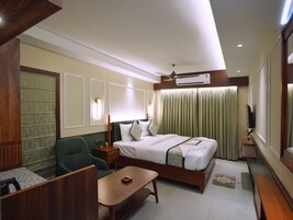 Ein Hotelzimmer mit Bett, Schreibtisch, Stuhl, Fernseher und Deckenventilator.