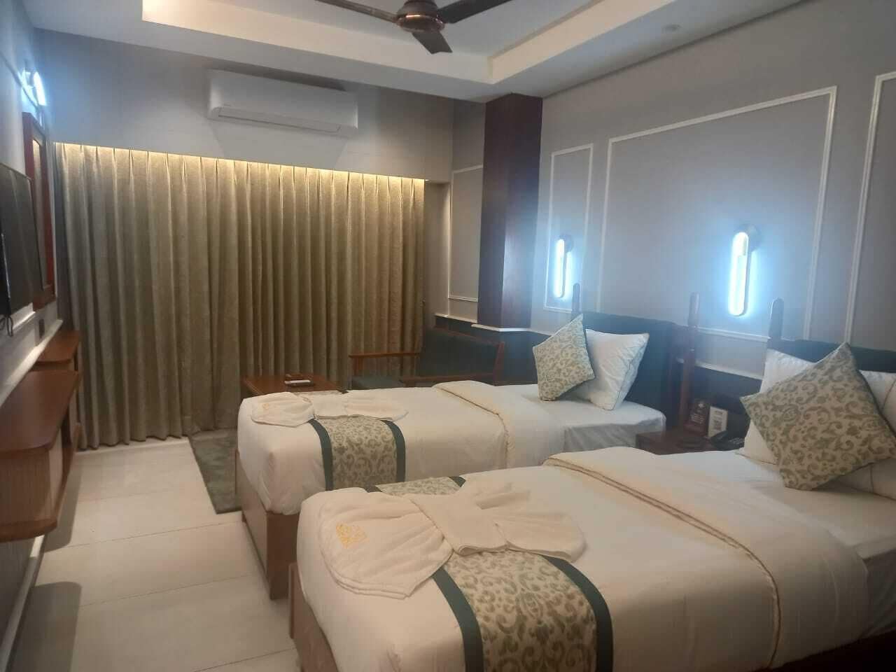 A hotel room with two beds, a desk, and a TV.
