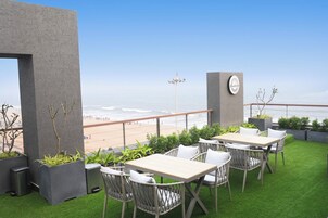Terraza en la azotea con vista a la playa, con mobiliario exterior y jardineras.