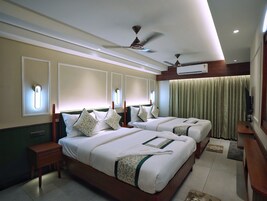 Habitación de hotel con dos camas, ventilador de techo, aire acondicionado y televisor.