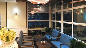 Un espace de détente moderne, doté de sièges confortables, de grandes fenêtres et d’un éclairage décoratif.