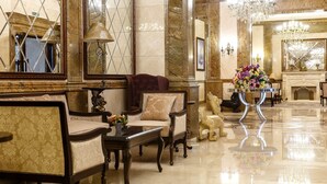 A luxurious lobby with marble floors, ornate furniture, and a chandelier. - Alanda Hotel (Astana)