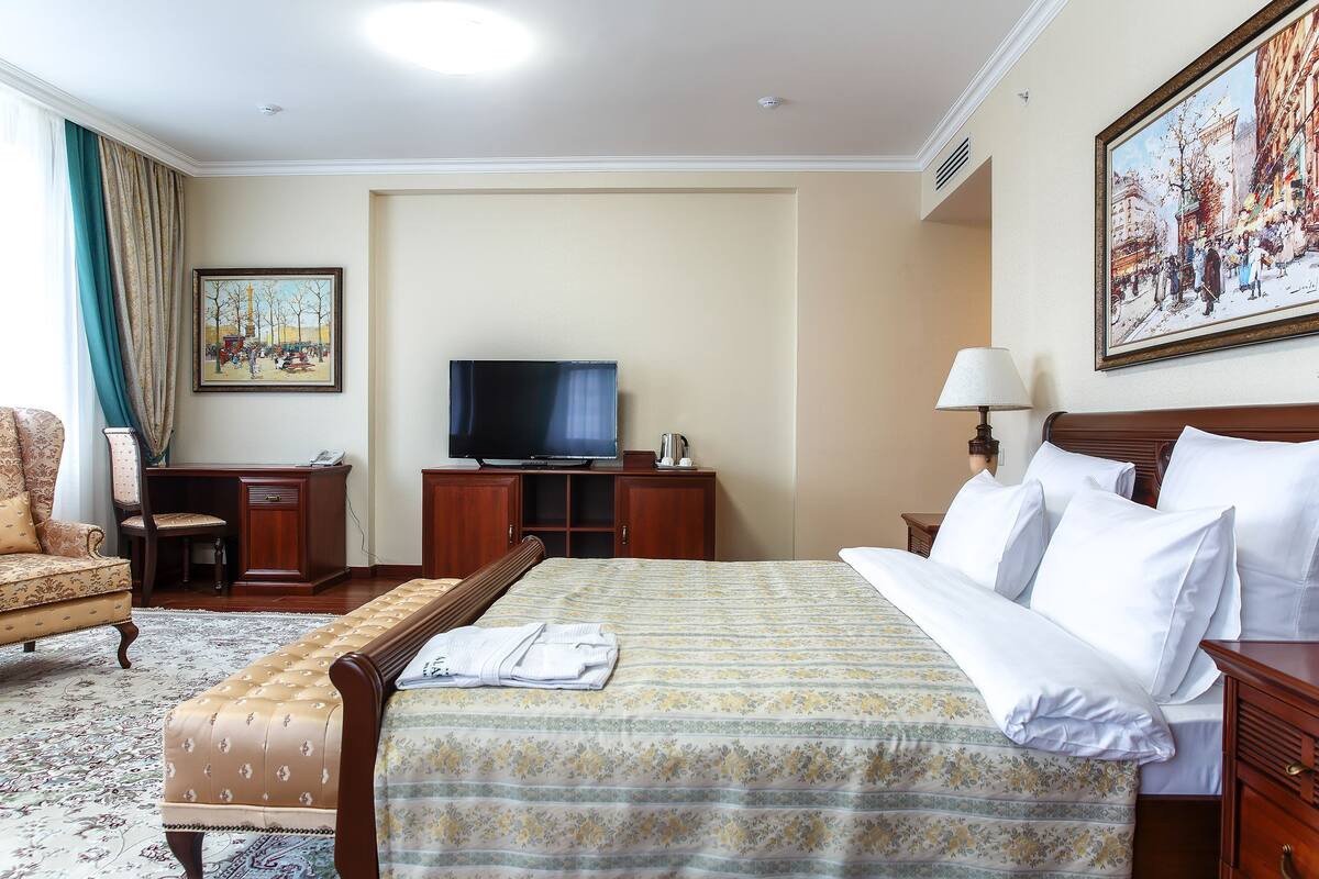 Ein Hotelzimmer mit einem großen Bett, einem Fernseher, einem Schreibtisch und einem Stuhl.