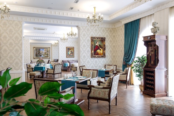 A formal dining room with wooden furniture, chandeliers, and a large painting on the wall.