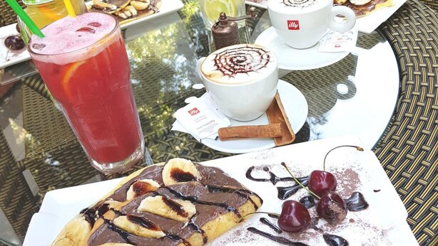 A table with various desserts and drinks, surrounded by wicker chairs and a glass table. - L Plaza Hotel (Tbilisi)