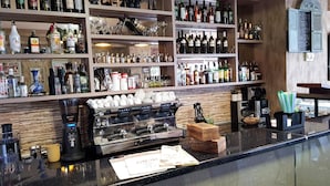 A bar area with shelves of various liquor bottles, a coffee machine, and a menu on the counter. - L Plaza Hotel (Tbilisi)