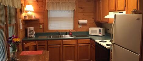 A compact kitchen with wooden cabinets, a sink, a microwave, and a refrigerator.