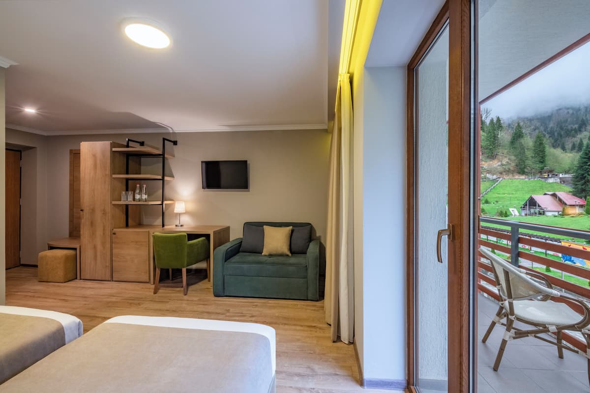Una habitación de hotel moderna con balcón, escritorio, sofá y dos camas.