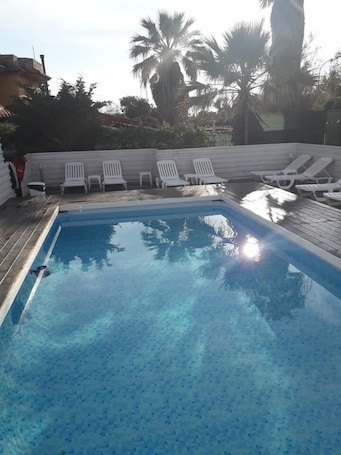 Una piscina al aire libre de temporada, sillones reclinables de piscina