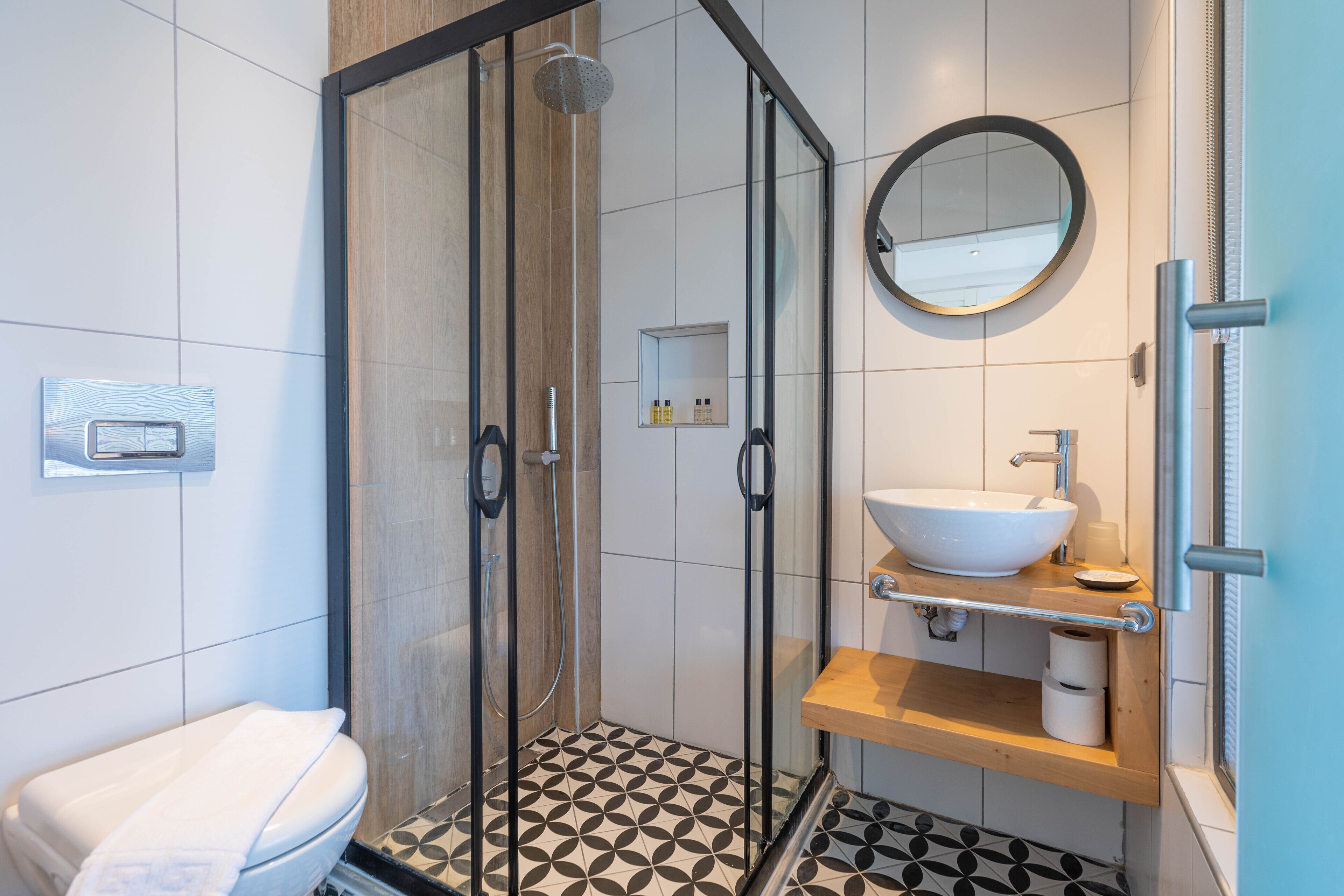 A modern bathroom with a glass-enclosed shower, a white sink, and a wooden vanity.
