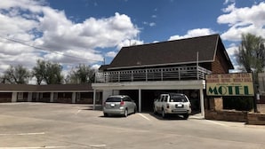 A motel with a signboard, two parked cars, and a clear sky. - Golden Arrow Motel (Lamar)