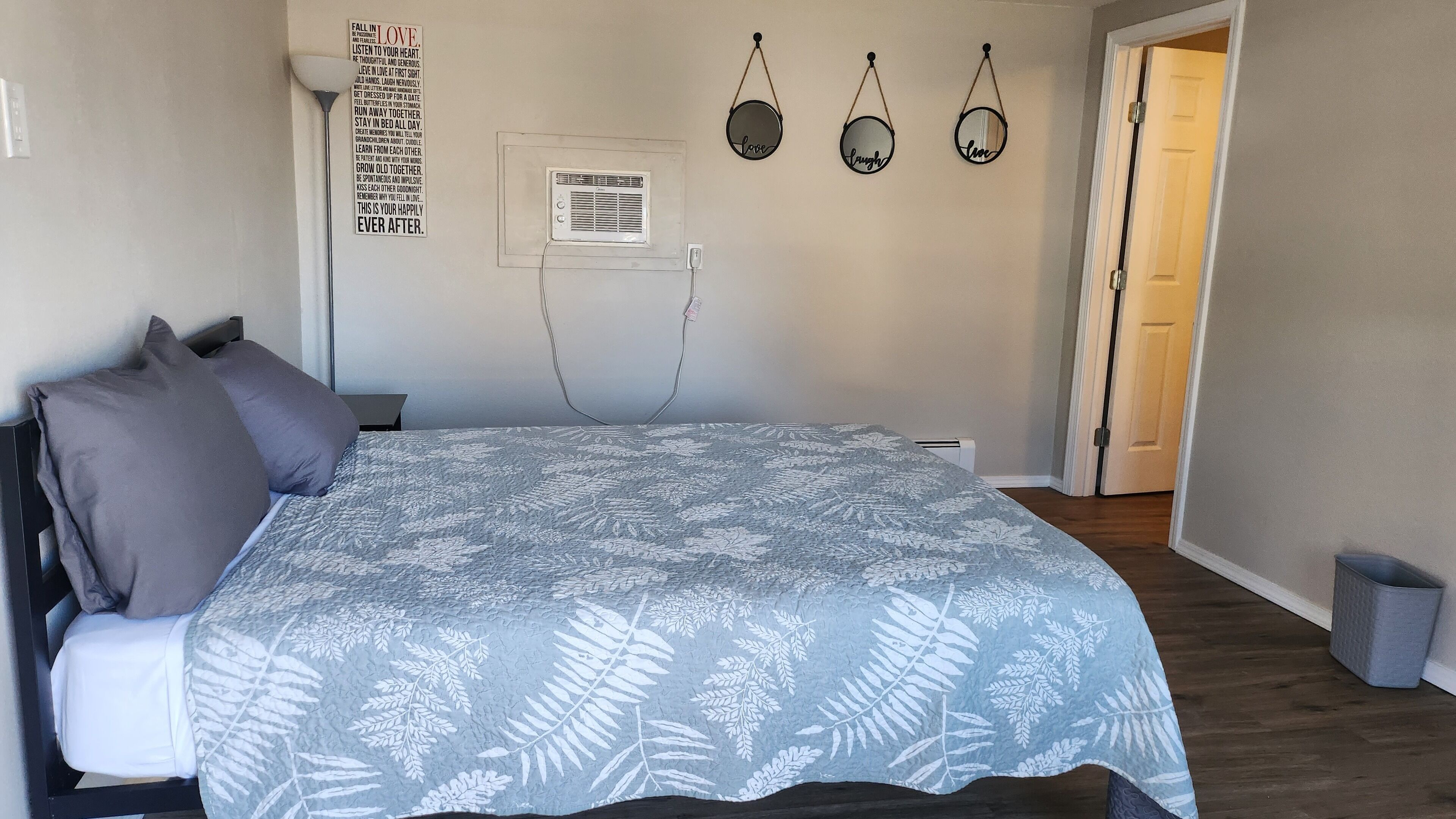 Un dormitorio con cama, una pared decorada y una puerta.