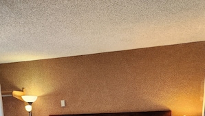 A large bed with a wooden headboard, two bedside tables, and a carpeted floor. - Golden Arrow Motel (Lamar)