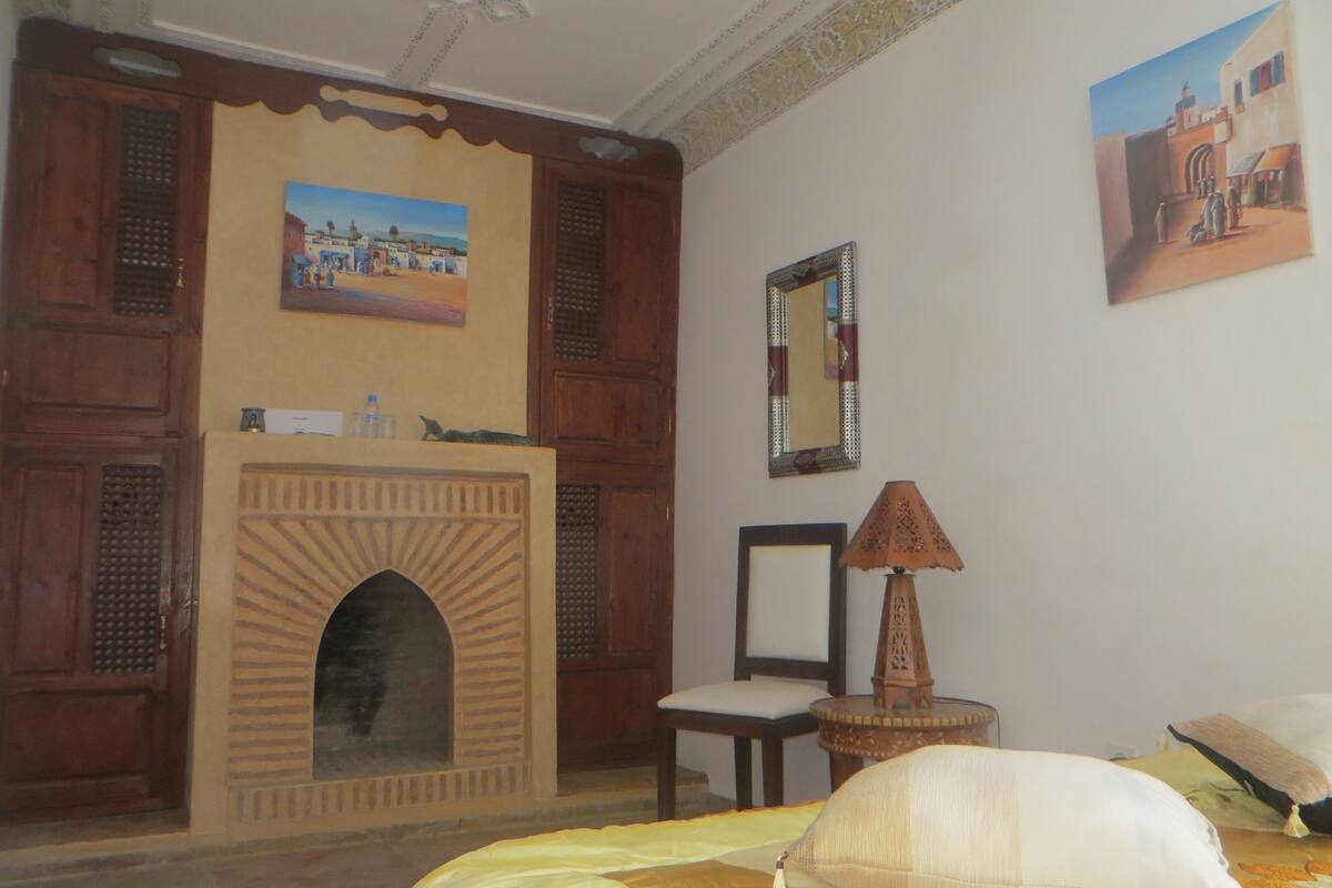 A room with a fireplace, a mirror, and a painting on the wall.