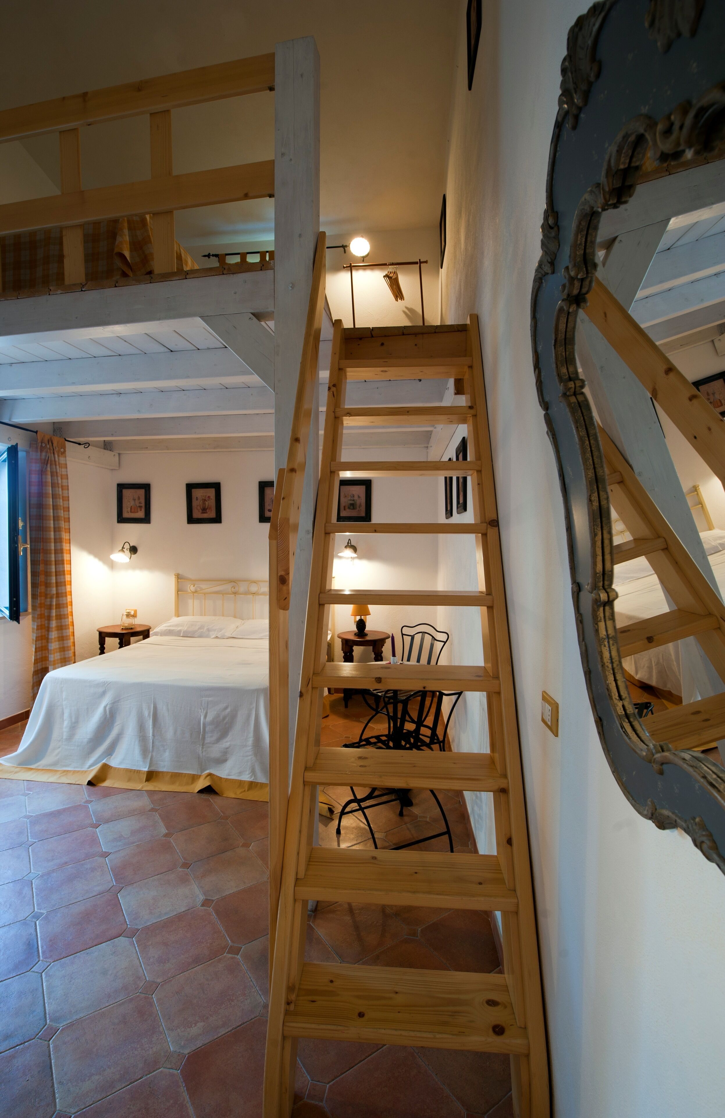 A bedroom with a wooden ladder, a bed, a desk with a chair, and a window with a curtain.