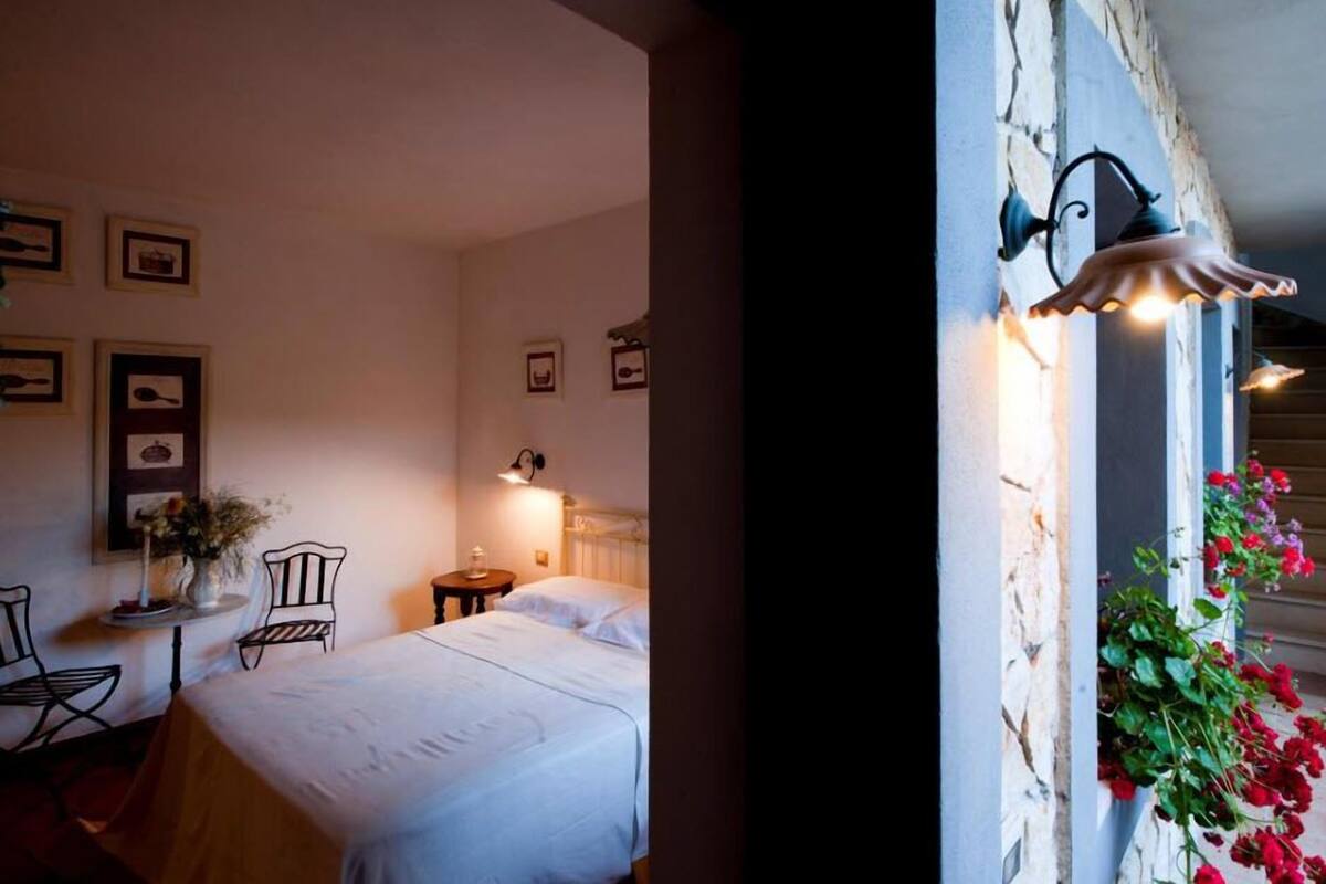 Un dormitorio acogedor con cama, mesita de noche, lámpara y decoración en la pared.