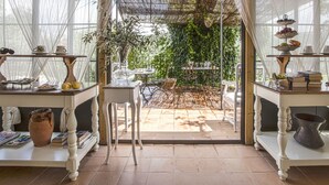 A conservatory with a glass ceiling, a dining area with white furniture, and a view of greenery outside.