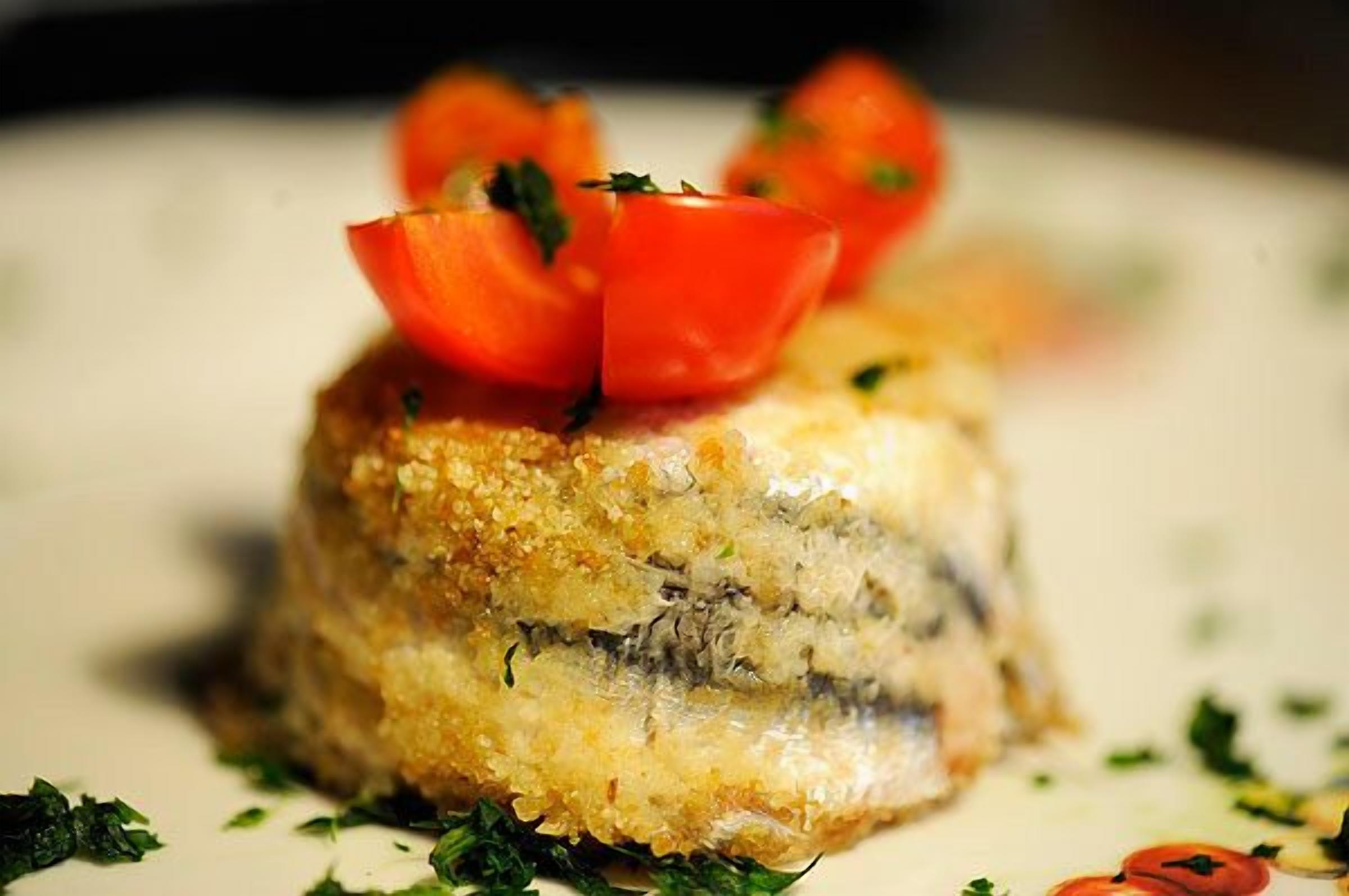 A dish with a golden-brown crust, topped with a slice of tomato and garnished with green herbs.